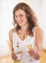 Woman holding wine bottle and glass. Photo : Daniel Grill
