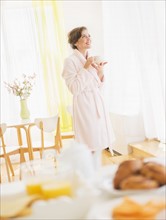 Woman in white robe drinking tea. Photo : Daniel Grill