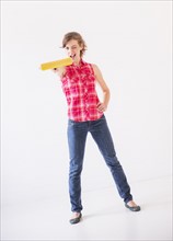 Studio shot of young woman holding paint roller. Photo : Daniel Grill