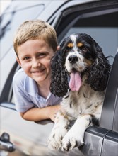 Boy (6-7) and his dog peeking from car window. Photo: Daniel Grill