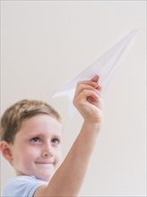Young boy (6-7) playing with paper plane. Photo: Daniel Grill