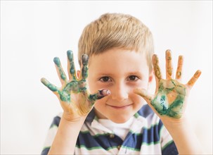 Young boy (6-7) showing hands stained with paint. Photo: Daniel Grill