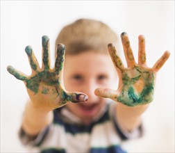 Young boy (6-7) showing hands stained with paint. Photo: Daniel Grill
