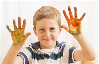 Young boy (6-7) showing hands stained with paint. Photo : Daniel Grill