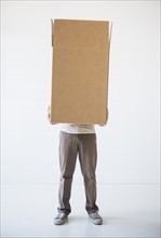 Mid adult man hiding inside of cardboard box. Photo : Daniel Grill