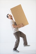 Mid adult moving cardboard heavy box. Photo : Daniel Grill