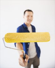 Man holding painting roll. Photo : Daniel Grill