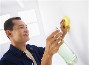 Man washing white walls with spray and yellow sponge. Photo: Daniel Grill