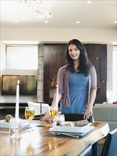 Young attractive woman standing behind table prepared for dinner.