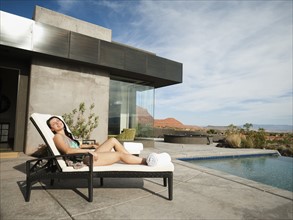 Young attractive woman sunbathing by swimming pool. Photo: Erik Isakson