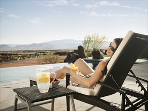 Young attractive woman enjoying cocktail by swimming pool. Photo: Erik Isakson