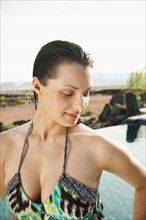 Young attractive woman standing on edge of swimming pool.