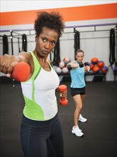 Two mid adult women exercising with dumbbells.