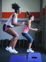 Two women in step aerobics class.