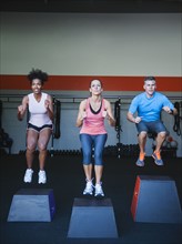 Three people in step aerobics class.
