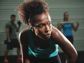 Portrait of mid adult woman in gym with people exercising in background.