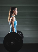 mid adult woman lifting barbell .