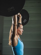 Mid adult woman lifting barbell .