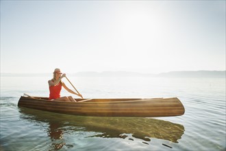 Portrait of young woman paddling canoe.