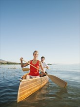 Portrait of two young people paddling canoe.