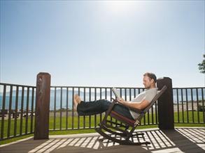 Mid-adult man relaxing on rocking chair.
