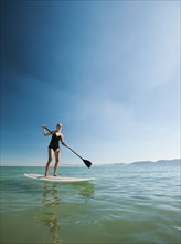 Young woman standing on paddleboard.
