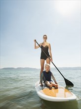 Portrait of young woman with daughter (4-5) on paddleboard.