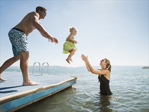 Parents playing with their daughter (2-3) in lake.