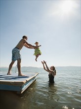 Parents playing with their daughter (2-3) in lake.