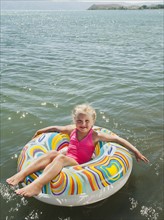 Portrait of girl (4-5) floating on water on inflatable ring. Photo: Erik Isakson