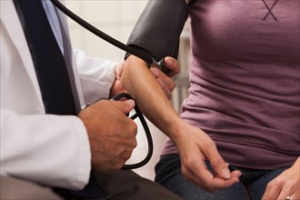 Close-up of doctor checking blood pressure with blood pressure cuff. Photo : Mike Kemp