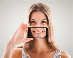 Woman smiling with smart phone in front of mouth, smile showing on screen of smart phone. Photo :
