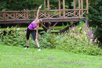 Young woman stretching her upper body in a field