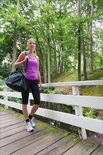 Young woman walking over a bridge carrying a sport bag