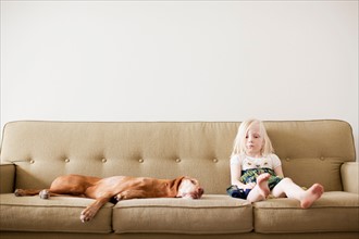 Girl (4-5 years) on couch with dog. Photo : Jessica Peterson