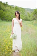 Portrait of woman wearing white dress and holding white flowers. Photo: Jessica Peterson