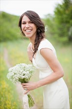 Portrait of happy woman holding flowers and smiling. Photo : Jessica Peterson