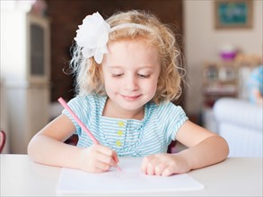 Girl drawing at table and smiling. Photo : Jessica Peterson
