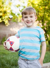 Boy smiling and holding soccer ball. Photo : Jessica Peterson