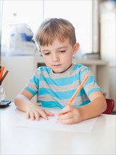 Boy drawing with pencil at table. Photo: Jessica Peterson