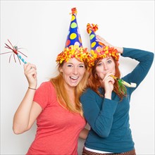 Studio Shot, Two young women wearing party hats. Photo : Jessica Peterson