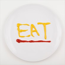 Word EAT written with mustard and ketchup. Photo: Jessica Peterson