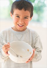 Boy (6-7) holding breakfast bowl.