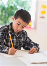 Boy (6-7) writing at school.