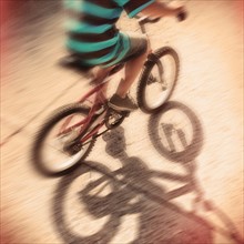 Low section of boy (6-7) riding bicycle.