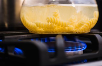 Close-up of pasta boiling on gas burner.