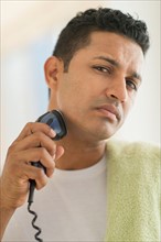 Man shaving with electric razor.