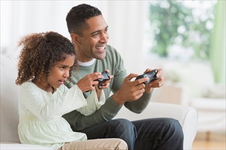 Father and daughter (6-7) playing video game.
