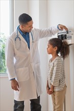 Male doctor examining girl (6-7) in his office.
