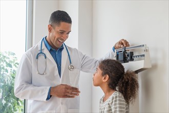 Male doctor examining girl (6-7) in his office.